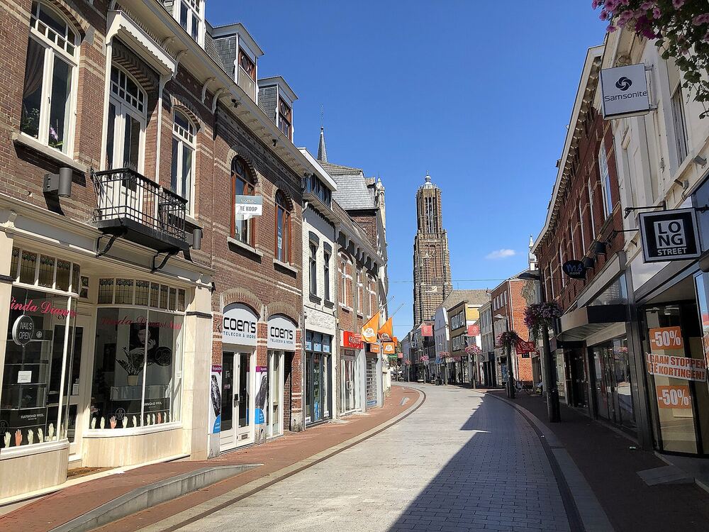 Een winkelstraat in Weert met de Sint-Martinustoren op de achtergrond